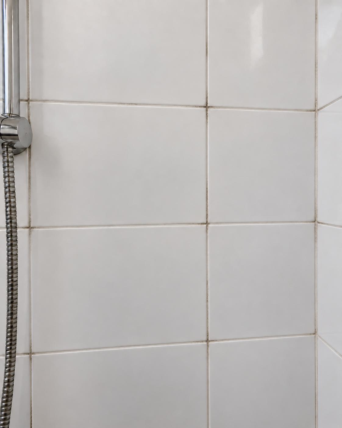 Dusche mit hellen Fliesen und dunkel verfärbten Fugen in der Vorher-Ansicht – KI-bearbeitetes Foto.