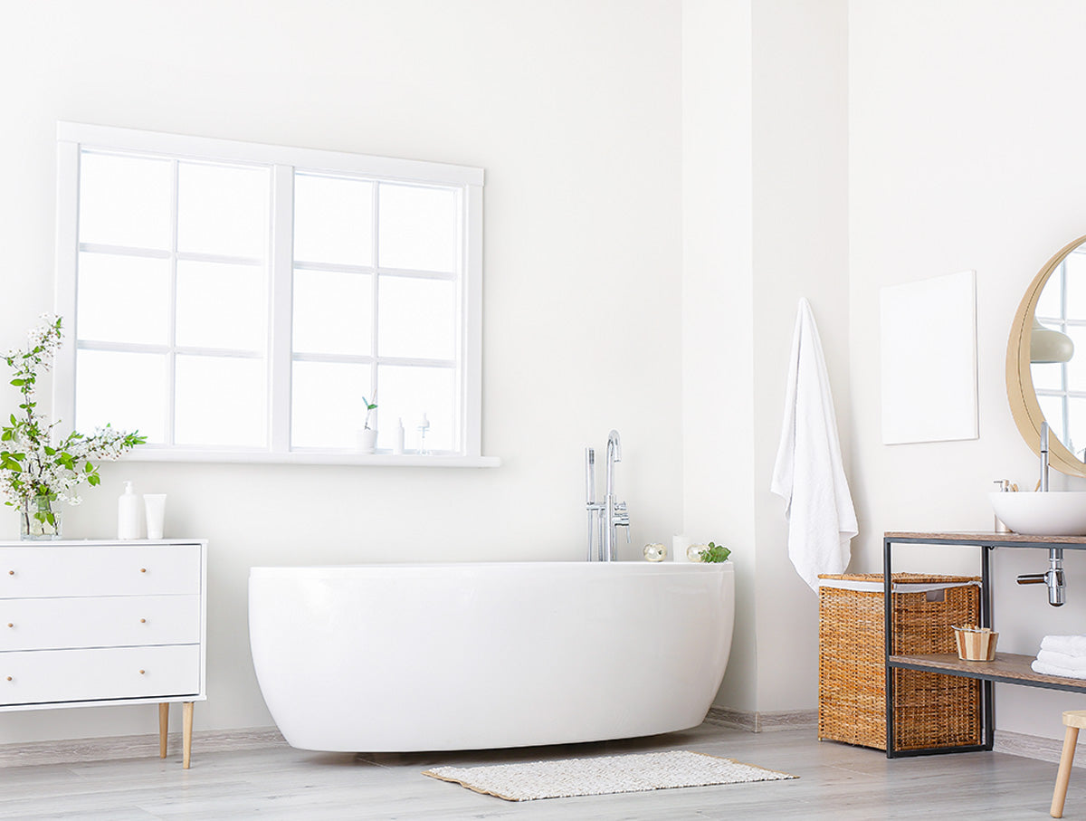 Helles Badezimmer mit weißen Wänden, Fenster und freistehender Badewanne.