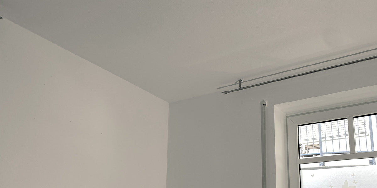 Wohnzimmer in der Nachher-Ansicht: weiß gestrichene Wand und Decke neben dem Fenster.
